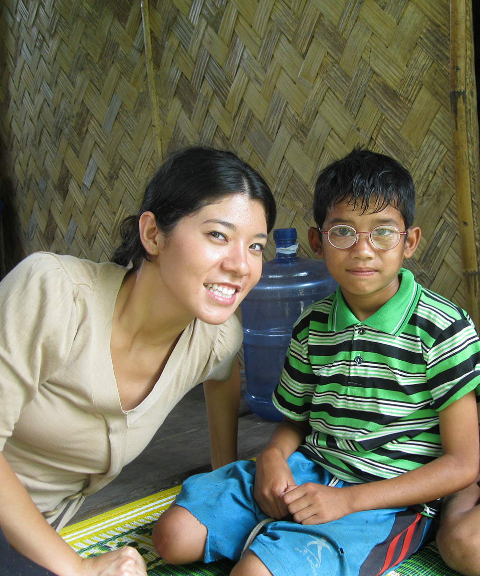 woman student sitting next to child in community space, Laos