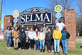 students standing at a sign that reads SELMA