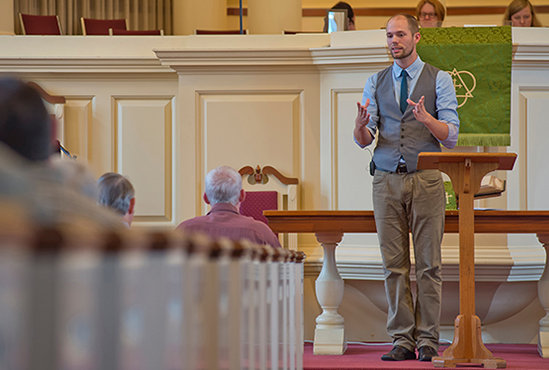 white male preaching in front of a congregation
