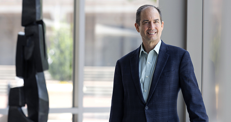 Jonathan Strom standing with windows behind and a sculpture to the left.