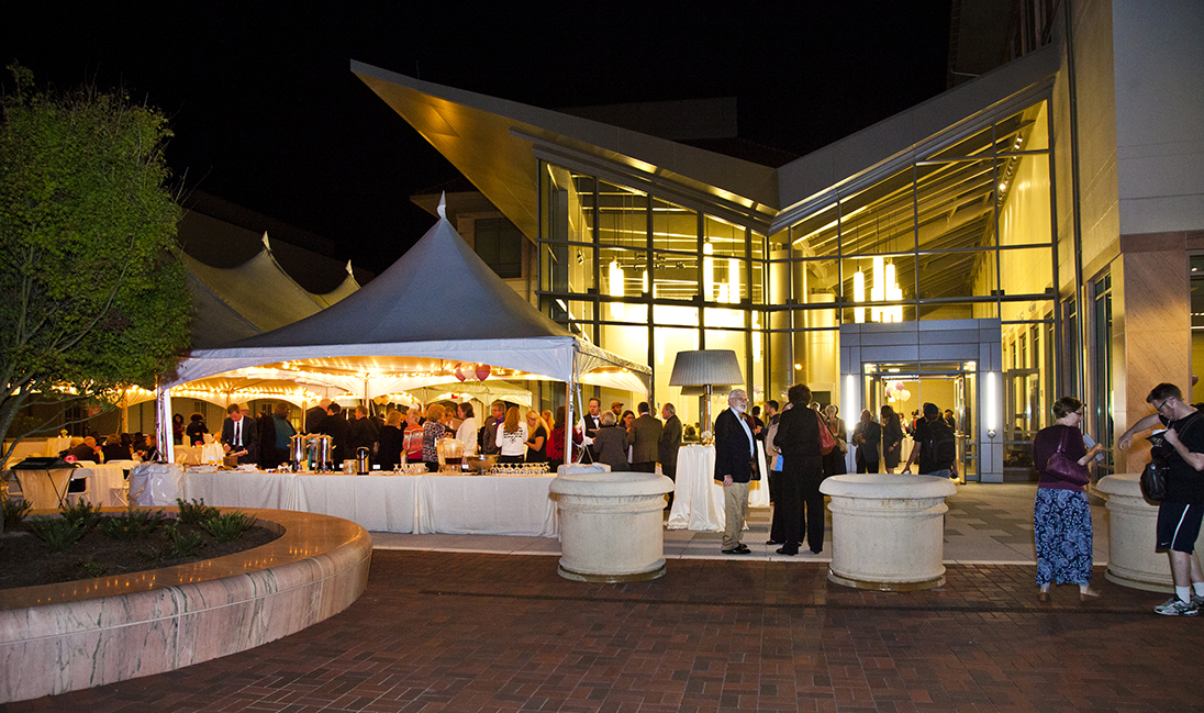 exterior of a modern building at night with lights on inside and people partying outside